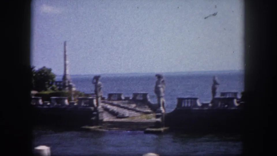 Continued pan across ornate stone waterfront ruins with tall spires and carved statues, Florida, circa 1960, on 8mm film.