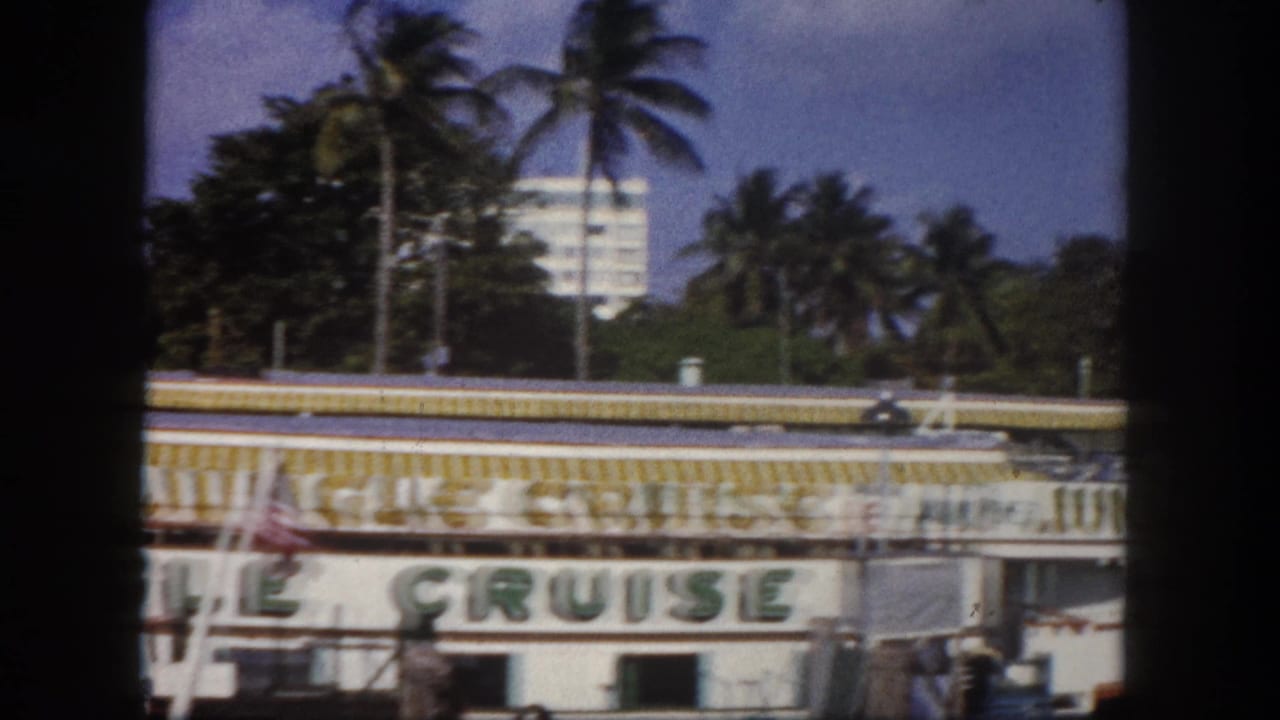Jungle Cruise attraction boat at Tampa waterfront, circa 1960 — full lettering visible, American flag flying, palm trees in background; 8mm film.