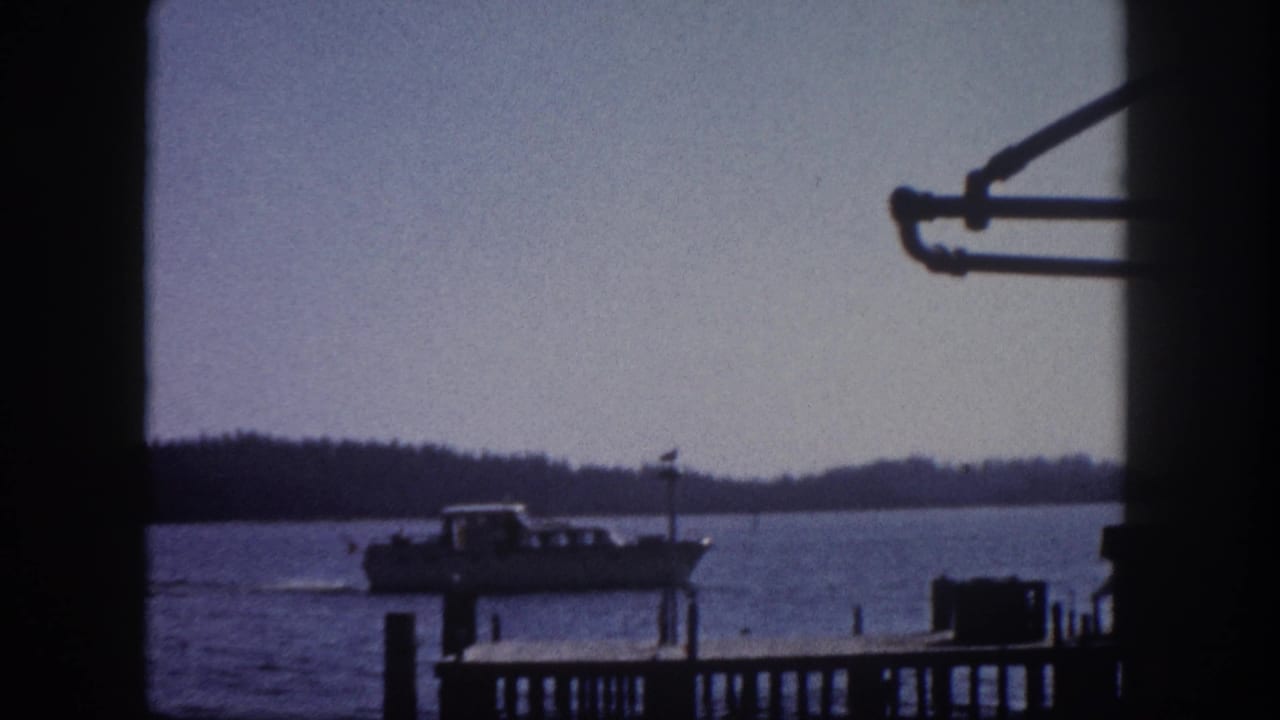 Vessel at wooden dock shot through window frame, early 1960s Florida bay waterfront, 8mm film.