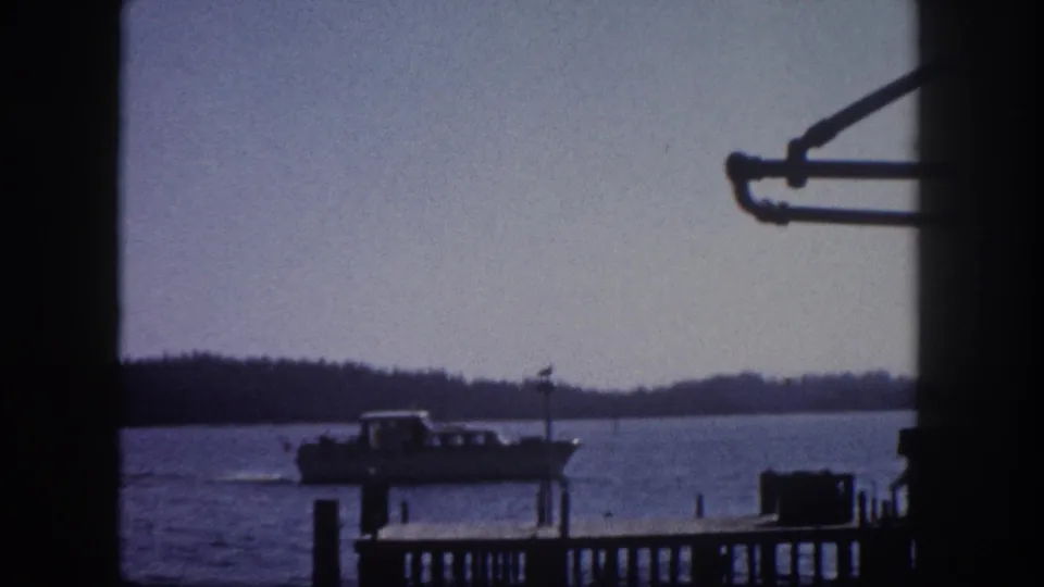 Vessel at wooden dock shot through window frame, early 1960s Florida bay waterfront, 8mm film.