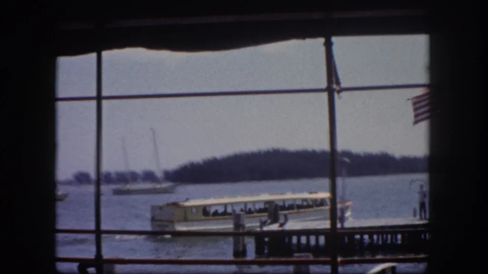 Large white excursion boat moored at dock, American flag flying, small figures on dock, Tampa Bay waterfront c.1960, 8mm film.
