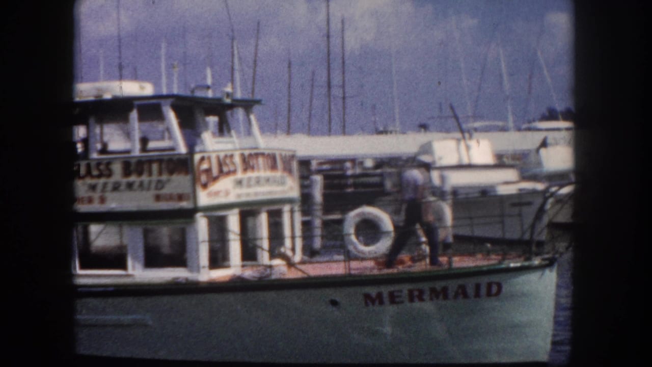 Glass Bottom Mermaid tourist vessel at Pier 9, Miami, circa 1960, crew member walking the deck with marina masts in background, shot on 8mm color film.