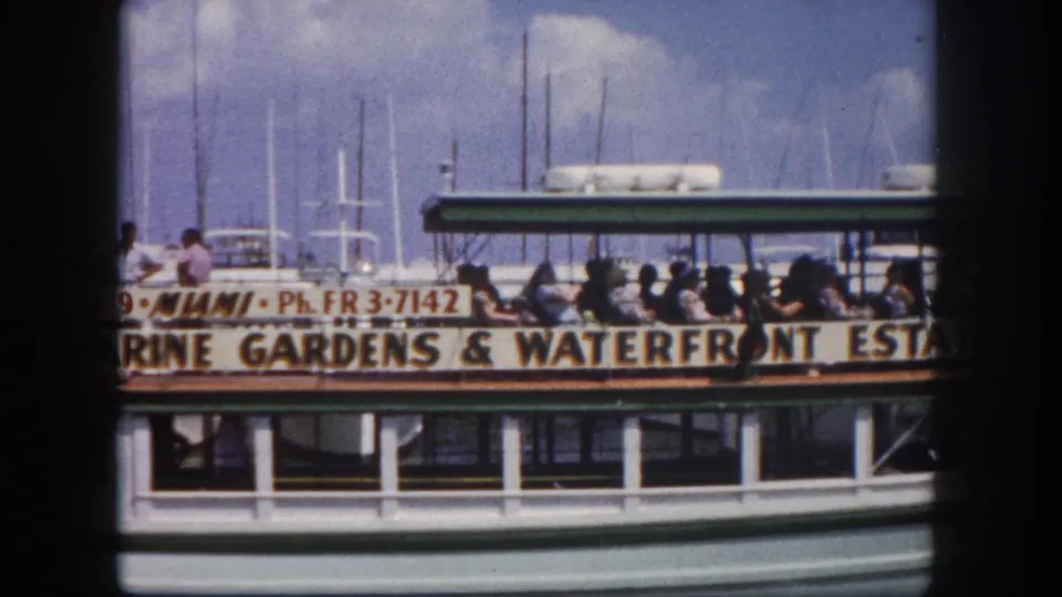 Tourists on the open-air Glass Bottom Mermaid boat, Miami, circa 1960; hull banner reads Marine Gardens & Waterfront Estates alongside telephone exchange FR 3-7142.