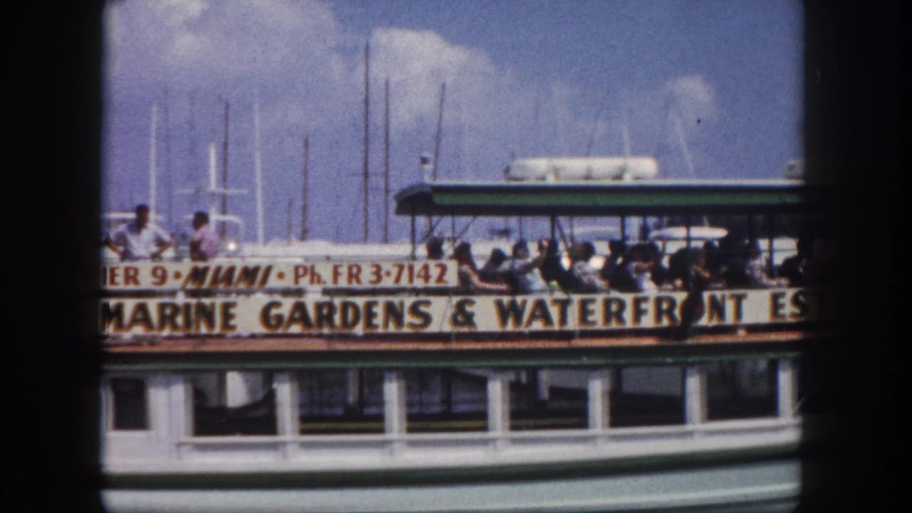 Double-decker tour boat with 'Marine Gardens & Waterfront Estate' and 'Pier 9 Miami' signage; passengers visible on the open upper deck.