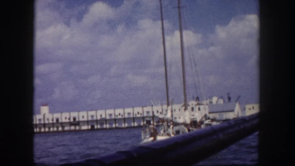 8mm shot circa 1960 showing a long white colonnaded waterfront pier with sailboat masts and harbor water, likely Tampa, Florida.