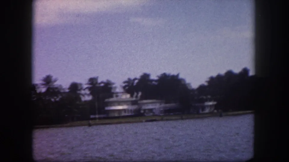 Broad Tampa waterway with palm-tree shoreline and large moored vessel, 8mm home movie, circa 1960.