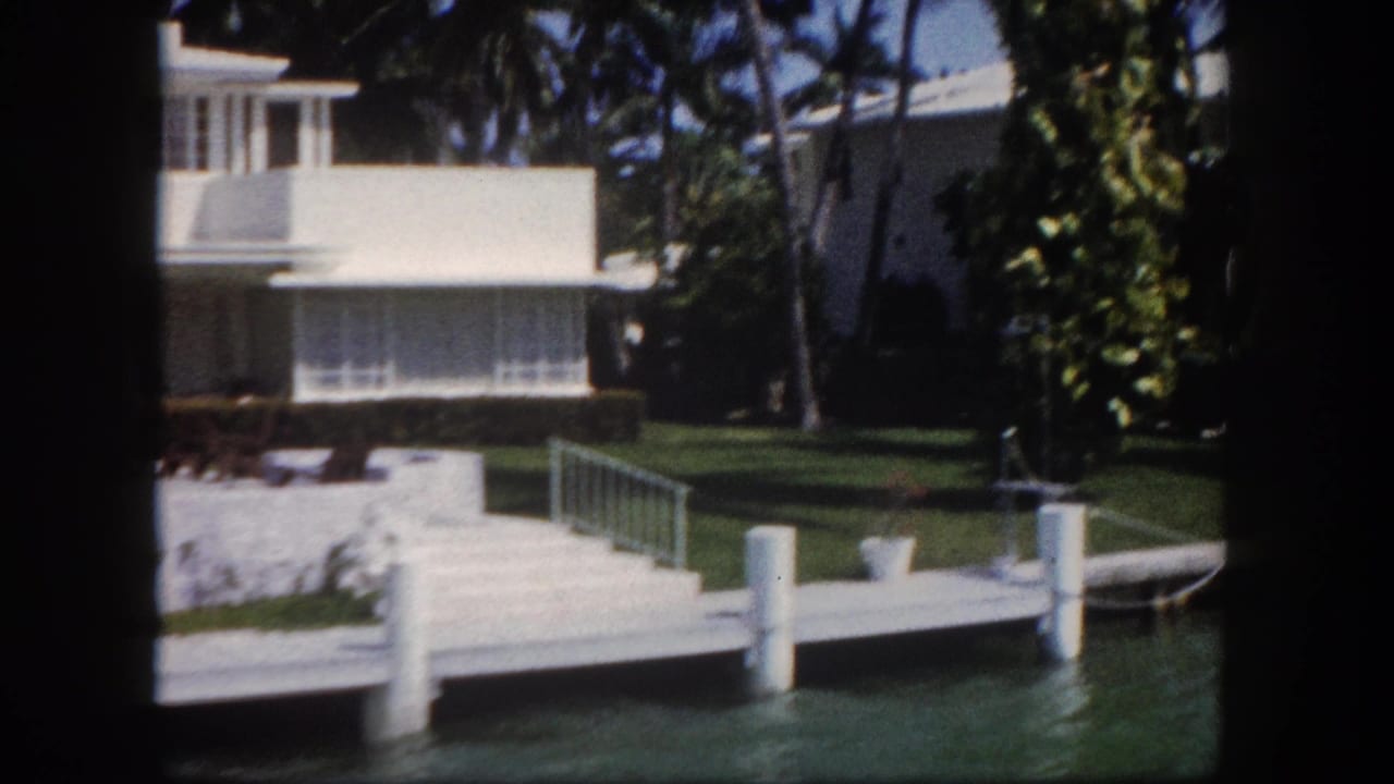Waterfront modernist house with concrete dock and pilings on a Florida canal, circa 1960, captured on 8mm home movie film.