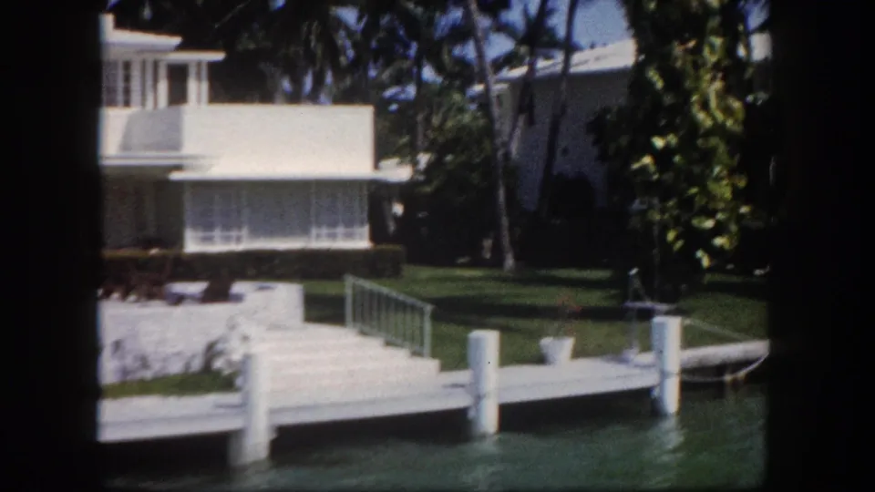 Waterfront modernist house with concrete dock and pilings on a Florida canal, circa 1960, captured on 8mm home movie film.