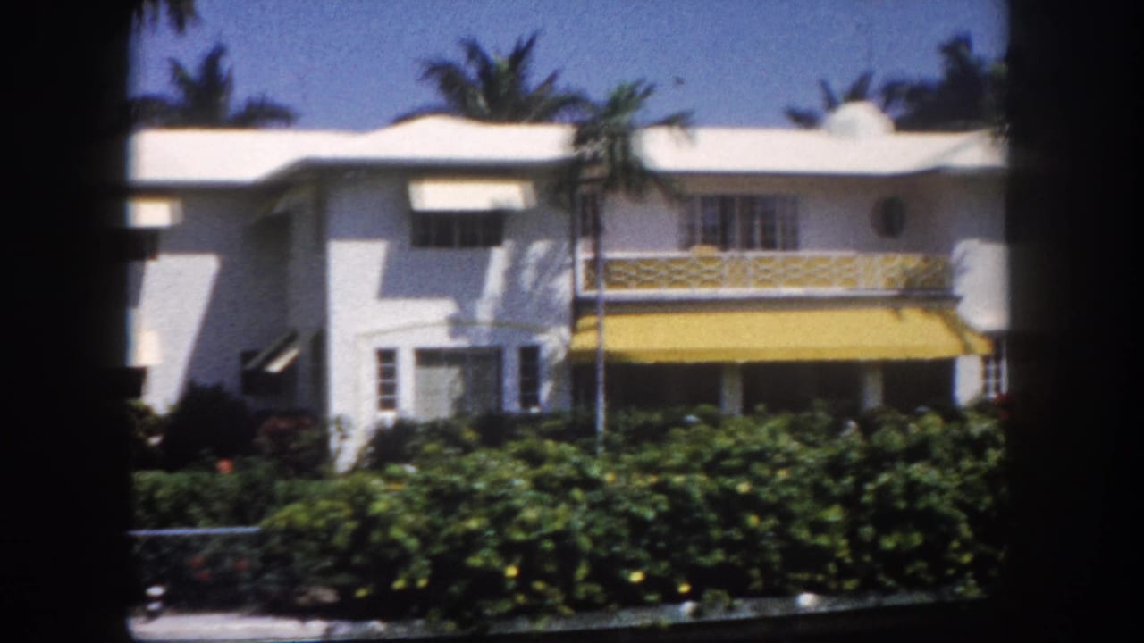 White Streamline Moderne-influenced Florida house with yellow-and-white awning and ornamental frieze band, Tampa, circa 1960, 8mm film.