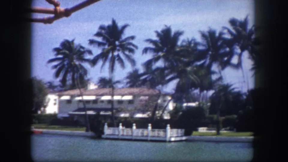 Waterfront estate with white stucco facade and dock structure across a Tampa-area canal, circa 1960, 8mm home movie from a passing boat.