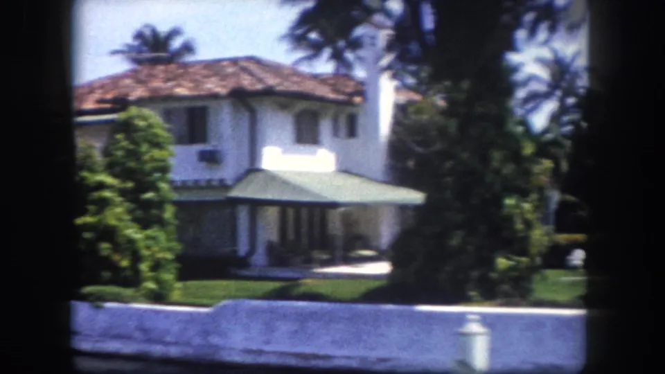 Two-story white stucco residence filmed from a canal in Tampa, Florida, circa 1960, within an 8mm film border.