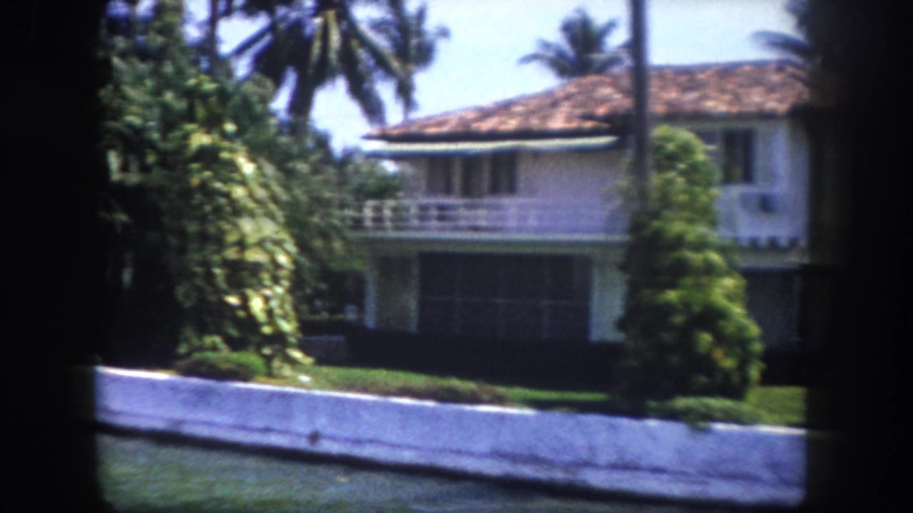 Two-story white stucco home with terracotta tile roof and upper balcony filmed from a Tampa canal, circa 1960, on 8mm film.