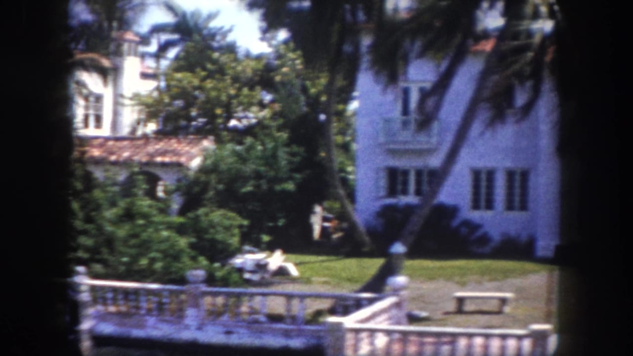 Two Mediterranean-style mansions with red tile roofs viewed across a white balustrade; a distant figure visible on the lawn, Tampa, c.1960.
