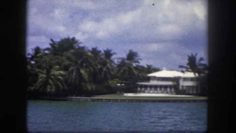 8mm footage circa 1960 Tampa, Florida: palm trees dominate the frame above a white waterfront structure viewed from a boat.