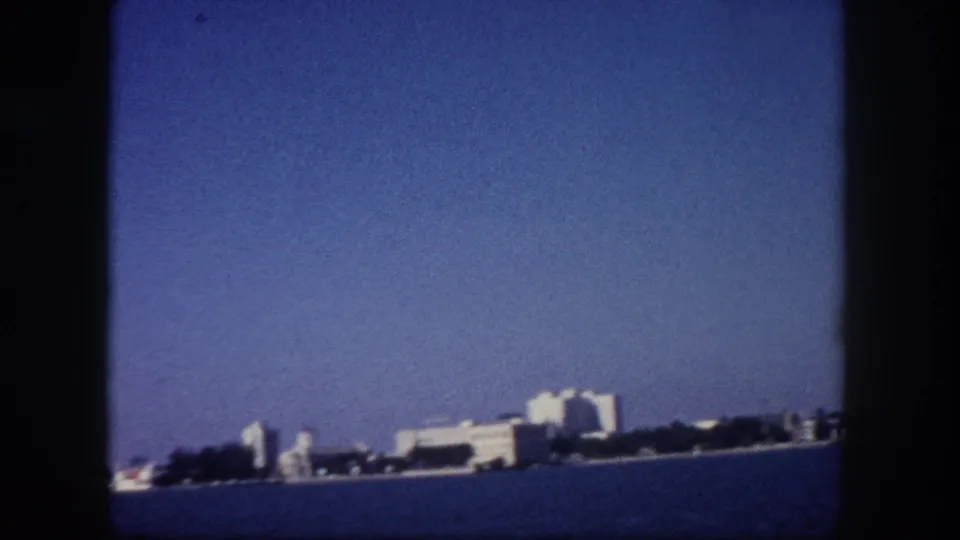 Tampa, Florida low-rise waterfront buildings seen from the water circa 1960, pale blue sky and faded 8mm color tones.