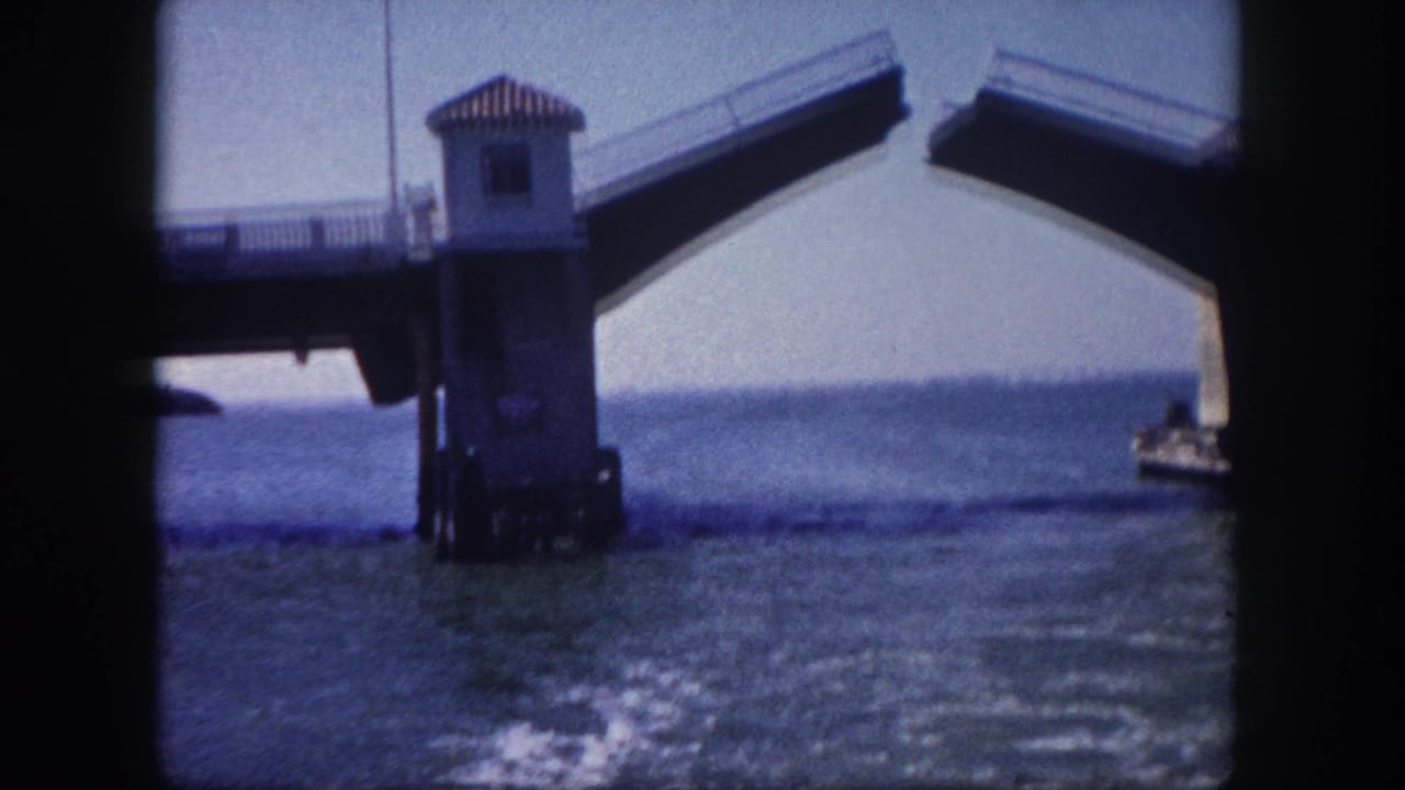 Raised bascule drawbridge with central control tower over Tampa Bay area water, circa 1960, captured on 8mm home-movie film.