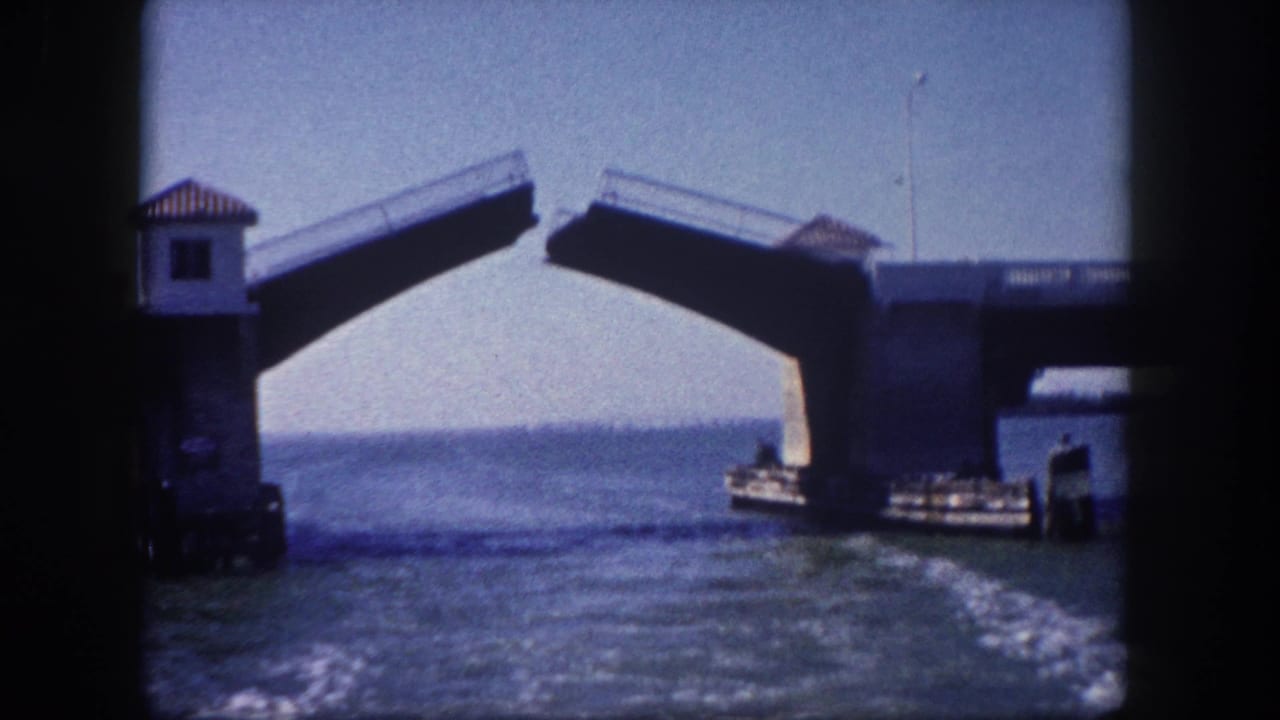 Raised bascule drawbridge over Tampa Bay area waterway with a boat passing beneath, circa 1960, on 8mm home-movie film.