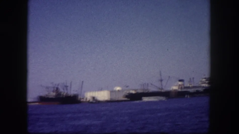 Multiple cargo vessels moored at Tampa port, Florida, circa 1960, photographed on 8mm film with blue-violet color cast and film frame border visible.