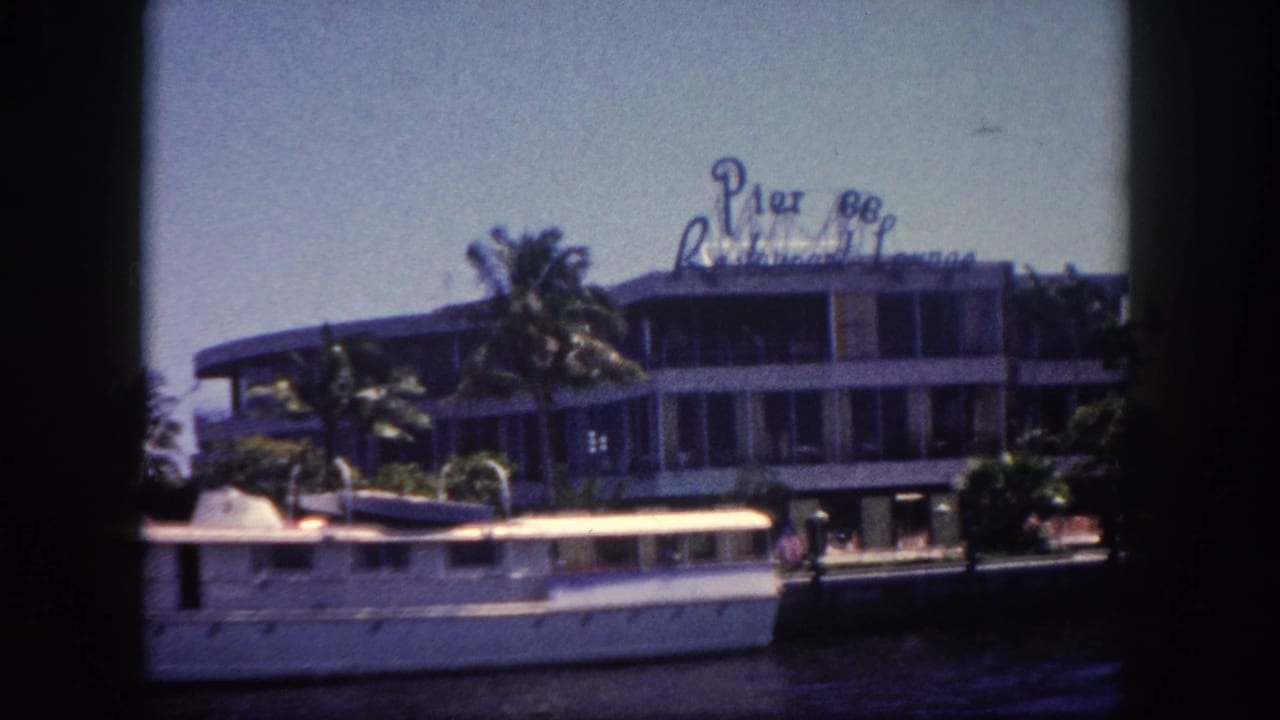 Multi-story waterfront building with "Pier 88 Restaurant Lounge" rooftop sign; large white vessel docked in foreground; palm trees; 8mm vignetting.