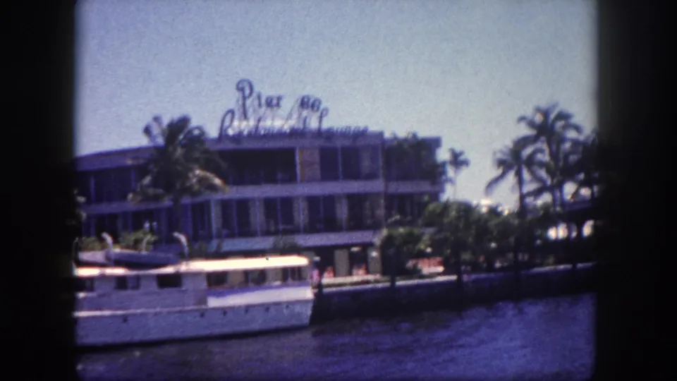8mm film frame of the Pier 88 Restaurant Lounge in apparent Tampa, Florida, circa 1960; camera has panned to reveal additional palm trees to the right of the building.