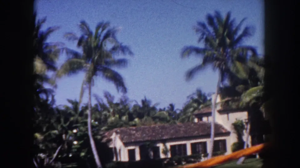 8mm color film frame circa 1960 showing palm trees framing a stucco house with tile roof along a Tampa, Florida residential waterfront.