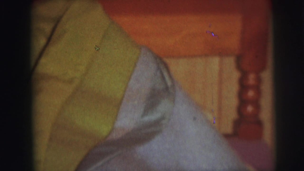 Close view of green and blue bedding on a wooden bed with paneled wall behind it.