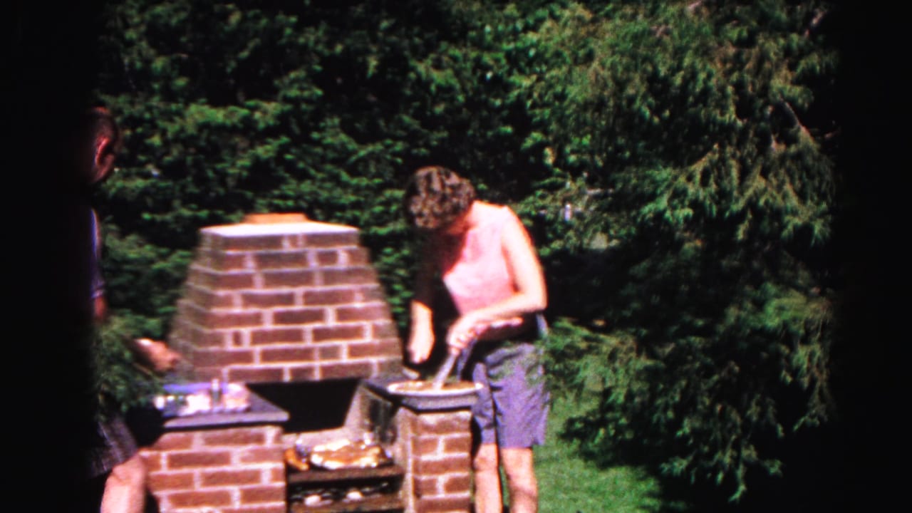 The 1963 backyard scene shows the woman continuing to cook beside the brick grill, with another person partly hidden in the dark center of the frame.