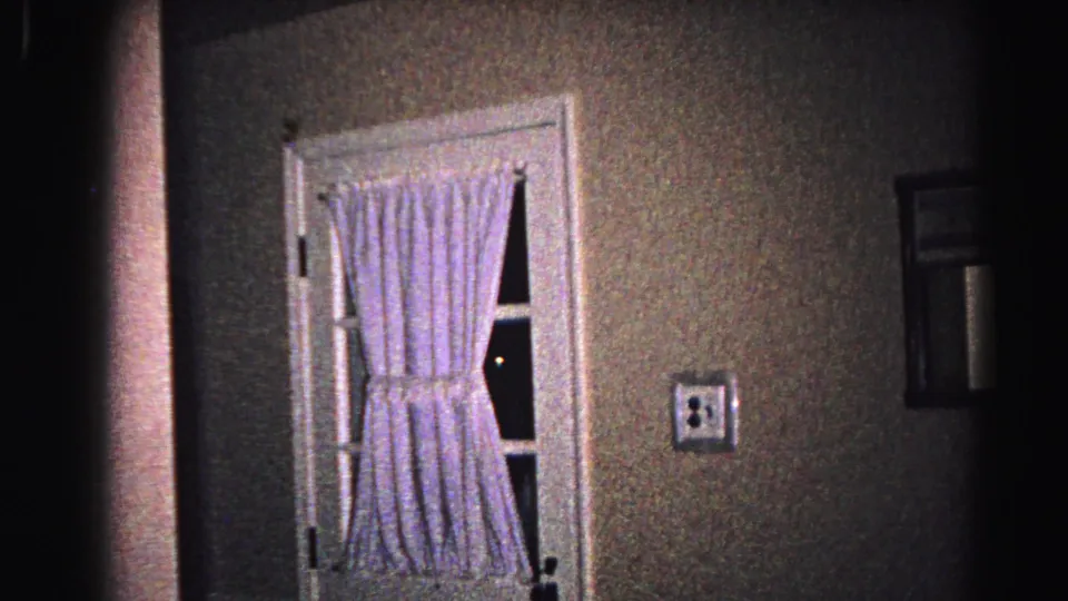 Interior view of a white-framed door with gingham curtains and a textured wall, from a 1963 Hagerstown Maryland home movie.