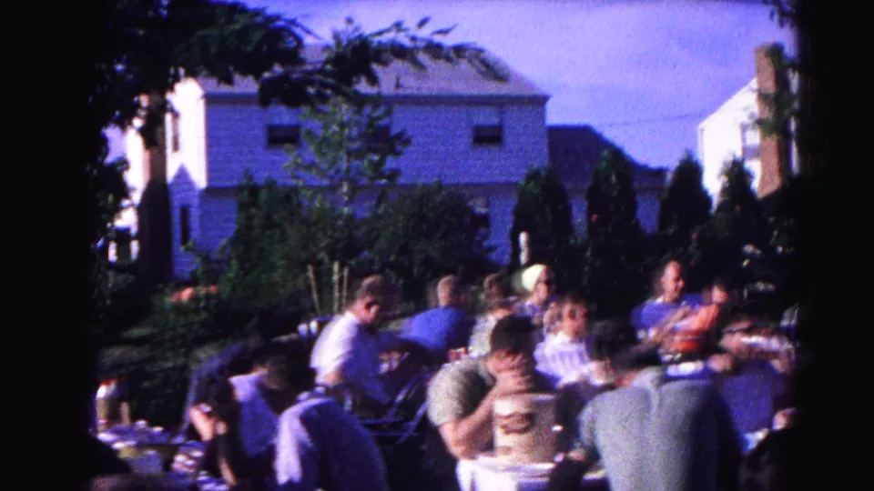 Cookout gathering in a Hagerstown, Maryland residential yard, circa 1963; adults at tables, branded cylindrical container visible in foreground.