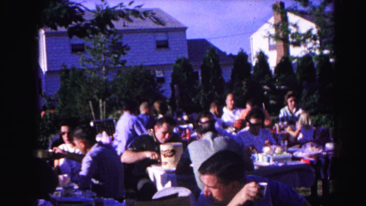 8mm home movie frame, c.1963, adults seated at white-clothed outdoor tables during a communal meal, likely in Hagerstown, Maryland.