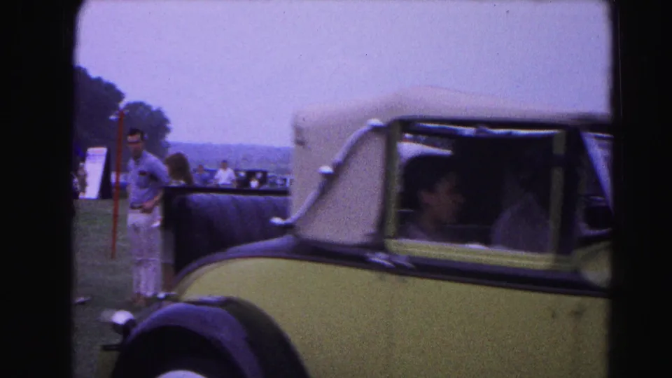 Passenger side of a pale yellow pre-war convertible at a 1963 Hagerstown, Maryland classic car show; a male attendee in early-1960s casual clothing stands alongside.
