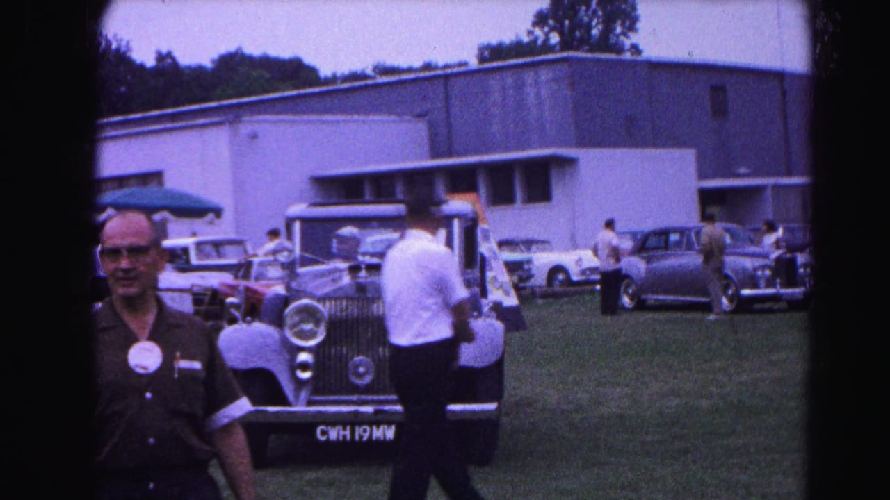 1963 Hagerstown, Maryland car show: attendee in dark shirt beside a light blue Rolls-Royce on a grassy field; other 1960s visitors and vehicles behind.