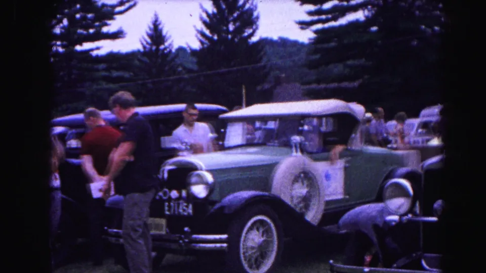 Dark green pre-war vintage convertible, plate partially reading E71454, at the 1963 Hagerstown car show; 1960s-dressed attendees examine the vehicle.