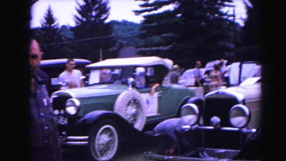 Close view of the green vintage convertible at the 1963 Hagerstown car show; man with sunglasses prominent in foreground among other period-dressed attendees.