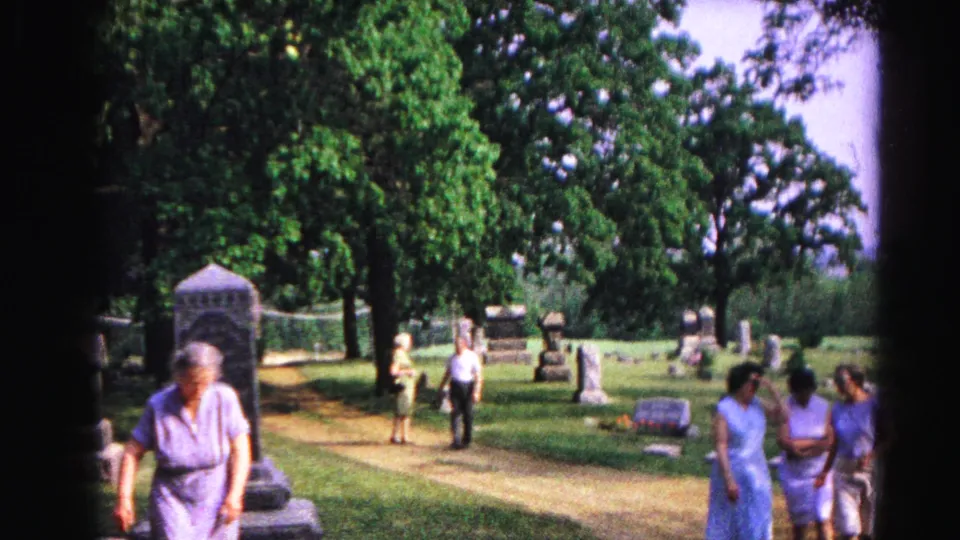 1963 8mm home movie: three women walk a cemetery path; headstones and a dark monument visible among mature trees, Hagerstown, Maryland.