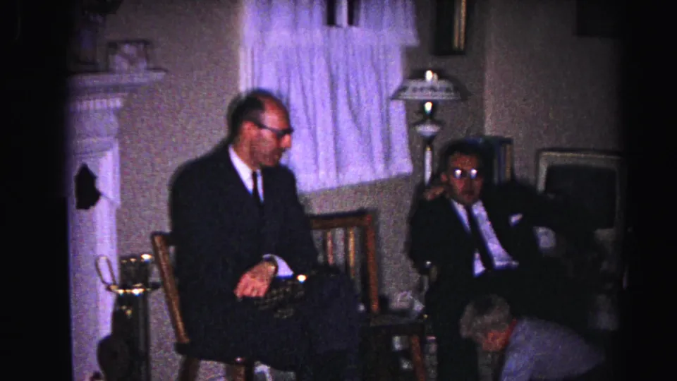 Two men in 1960s dark business suits and glasses seated in a domestic living room in what may be Hagerstown, Maryland, circa 1963.