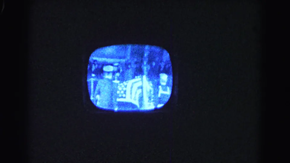 8mm home-movie shot of a rounded-corner CRT television in a dark room, its screen showing a grainy monochrome broadcast, Hagerstown, Maryland, 1963.