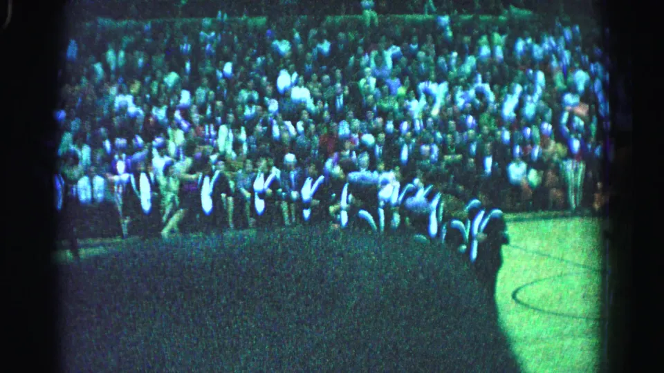 Elevated 8mm shot of dense outdoor crowd, likely Hagerstown Maryland 1963, with large foreground shadow and characteristic green film tint.