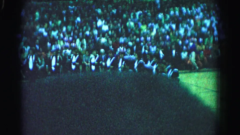 Closing 8mm frame of large Hagerstown Maryland outdoor gathering, 1963, crowd densely packed on grass under natural daylight.