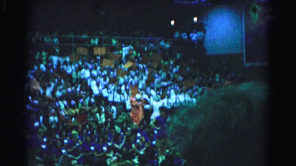 Packed stadium crowd at nighttime sporting event, Hagerstown, Maryland, circa 1963; blue-green 8mm color cast from artificial stadium lighting.