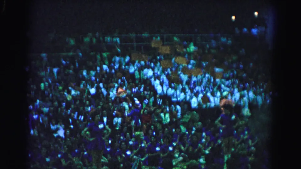 Densely packed crowd in stadium bleachers, Hagerstown, Maryland, circa 1963; 8mm color shift and grain characteristic of available-light film.