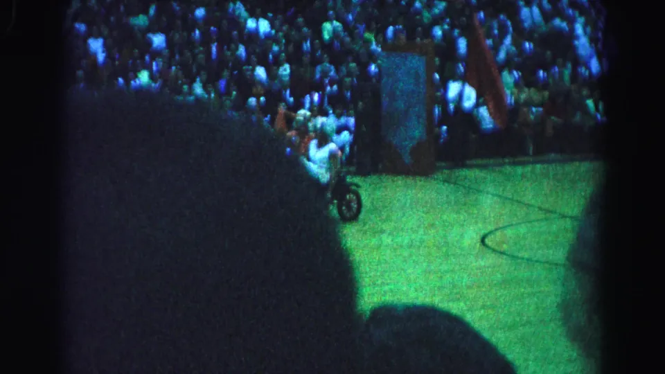 Costumed performers on a small motorized vehicle near the sideline of an indoor basketball court at an apparent 1963 Hagerstown, Maryland arena event, captured on grainy 8mm film.