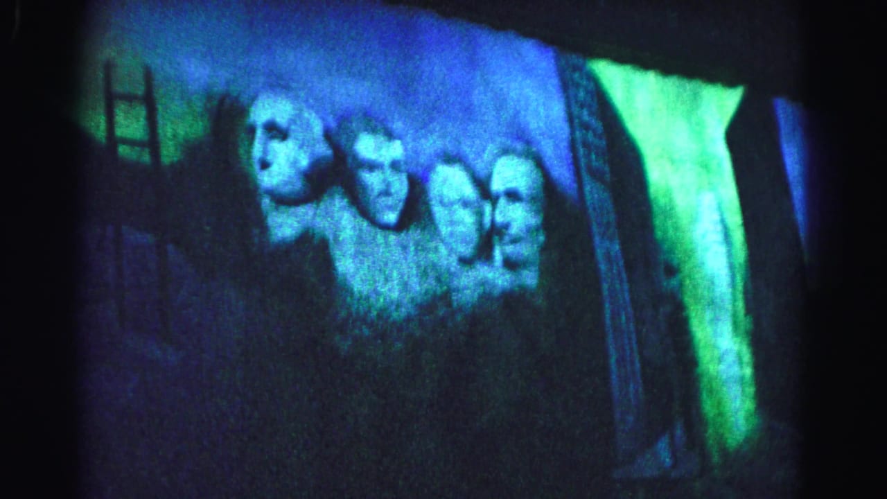 Four projected Mount Rushmore presidential faces bathed in blue and green colored light, 8mm film circa 1963.