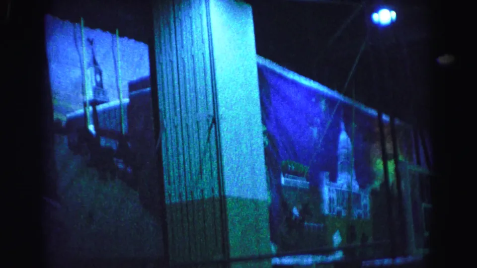 8mm film frame near clip end: vertical building column dominates center, bright blue point-source light visible upper right, Mount Rushmore projection nearly exited frame, Hagerstown area circa 1963.