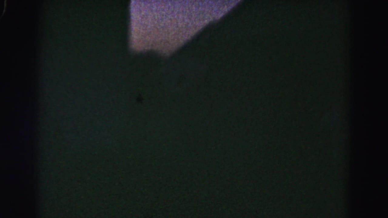 Second dark underexposed interior frame with purple-tinted ceiling area and shadowed walls, nearly identical to the opening frame.