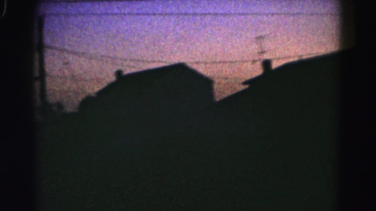 Silhouetted rooftops and overhead wires under a purple dusk sky.