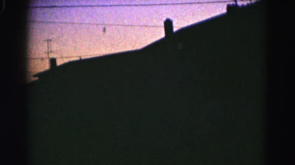 A silhouetted Hagerstown roofline with chimney forms and overhead utility wires crossing a soft twilight sky.