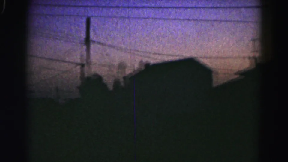 1963 Hagerstown home-movie frame showing a dark roofline, utility pole and wires under a purple dusk sky.