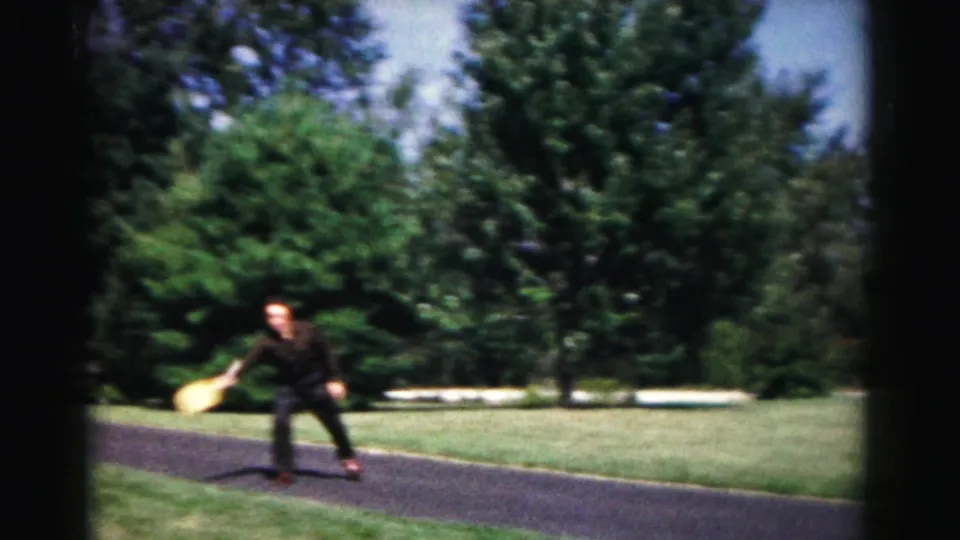 A dark-clothed player moves toward the camera with a racket in 1963 Hagerstown home-movie footage of informal outdoor play.