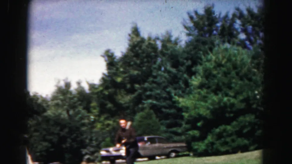 Near the end of the clip, the man leans into the paddle-ball play in the Hagerstown yard, framed by lawn, driveway, car, and trees.